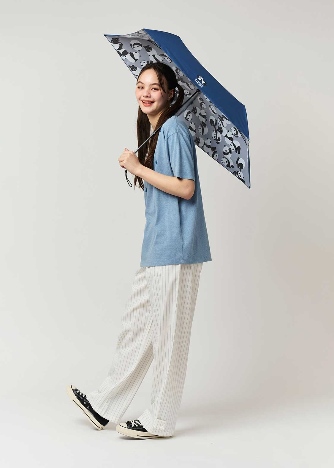 Person holding a panda patterned umbrella against a plain background