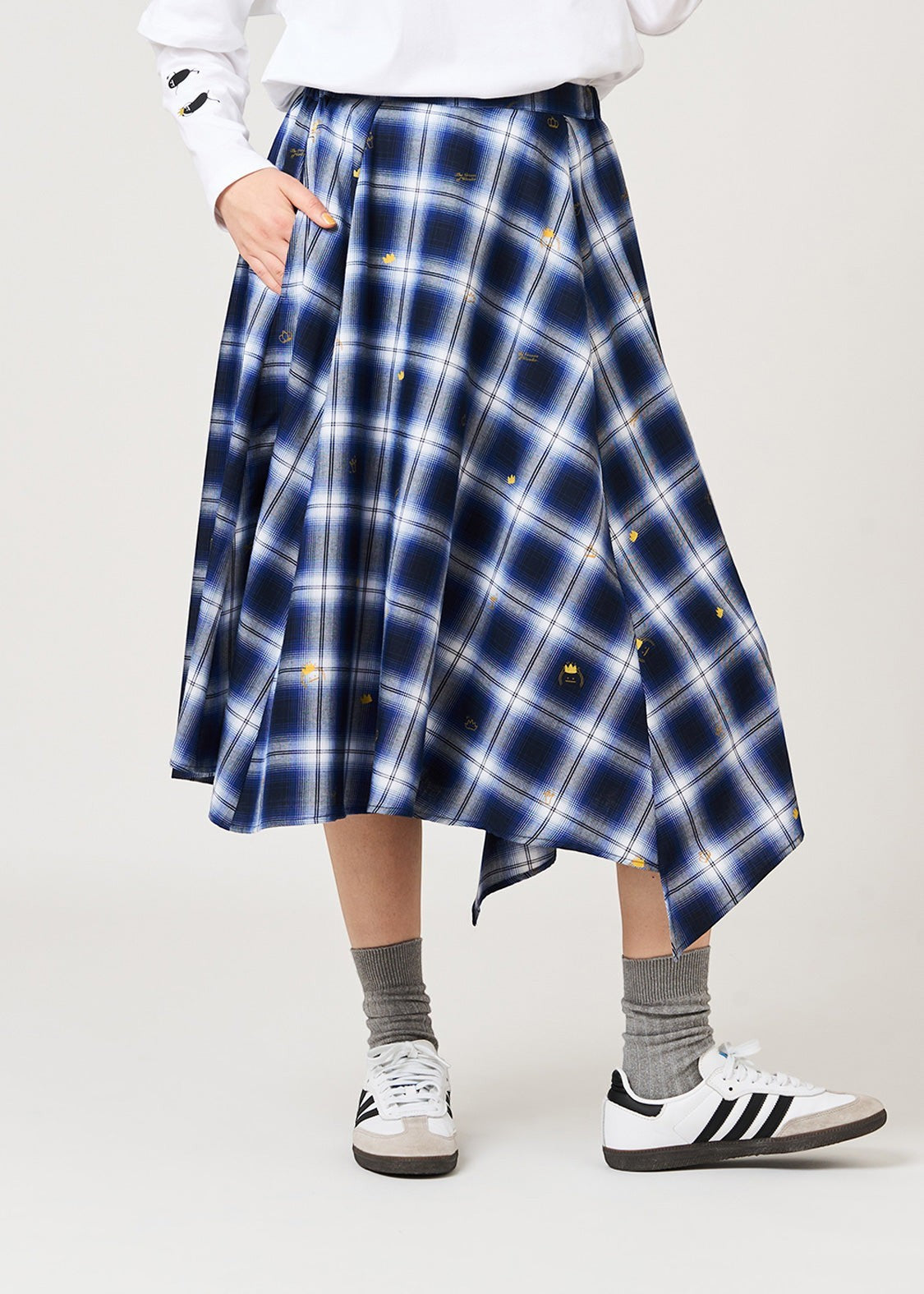 Via Artists unisex check skirt with irregular hem, blue plaid pattern, small crown embroidery, and side pockets.