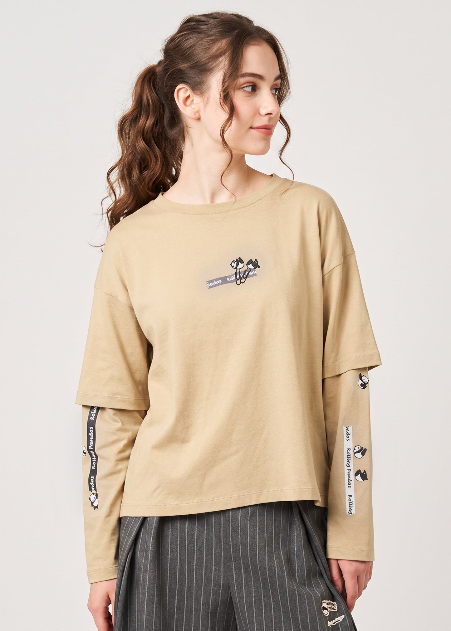 Via Artists beige long-sleeve layered cotton t-shirt featuring embroidered rolling pandas and desk-themed graphics.