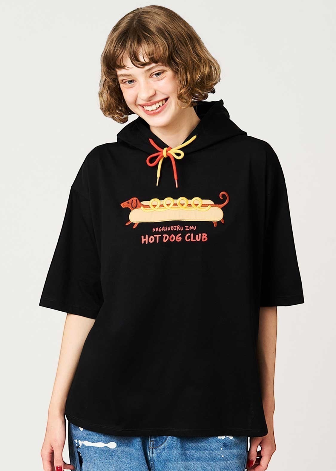 Via Artists black short-sleeve hoodie featuring a long dachshund hot dog graphic and colorful drawstring detail.