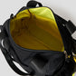 Via Artists Boston shoulder bag with black nylon exterior and bright yellow interior lining, top view.
