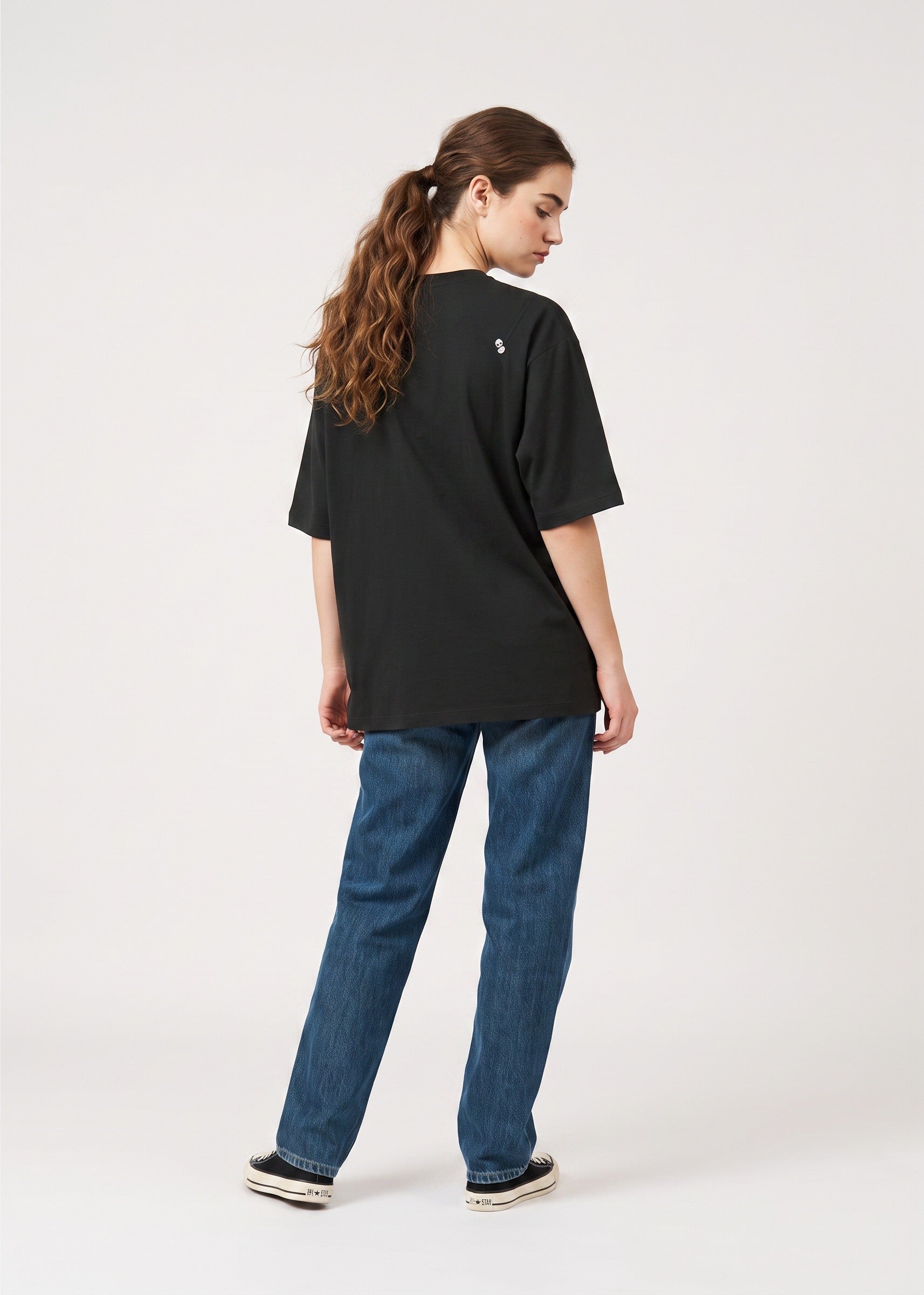 Via Artists black peach-brushed cotton unisex t-shirt with 5/8 sleeves, worn by a woman with blue jeans, back view.