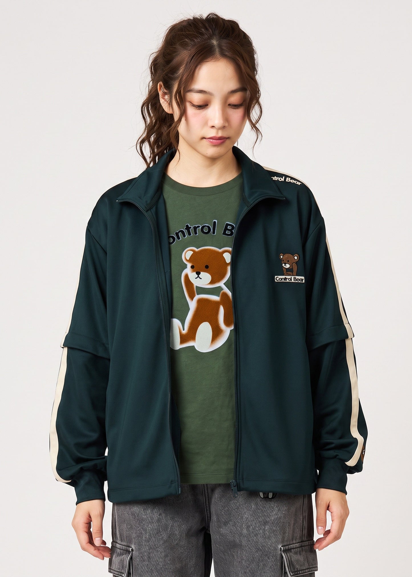 Via Artists dark green unisex track jacket with detachable sleeves, velour tape accents, and Control Bear embroidery.