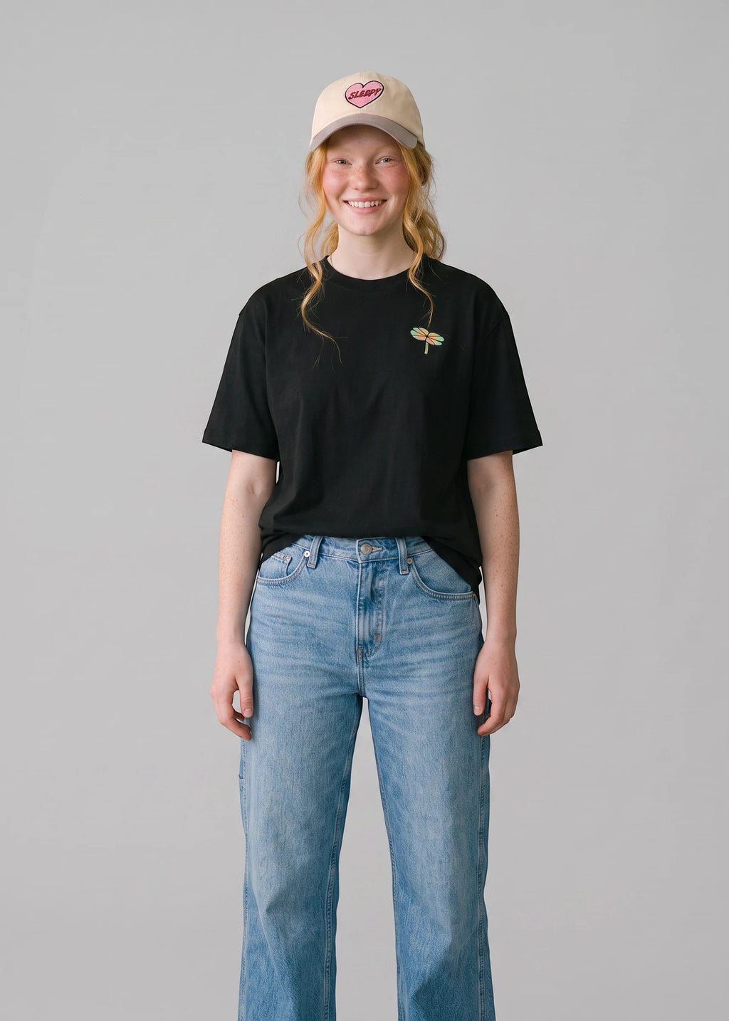 Via Artists Helcovell Guard black oversized cotton t-shirt with small dragonfly graphic worn by a smiling woman
