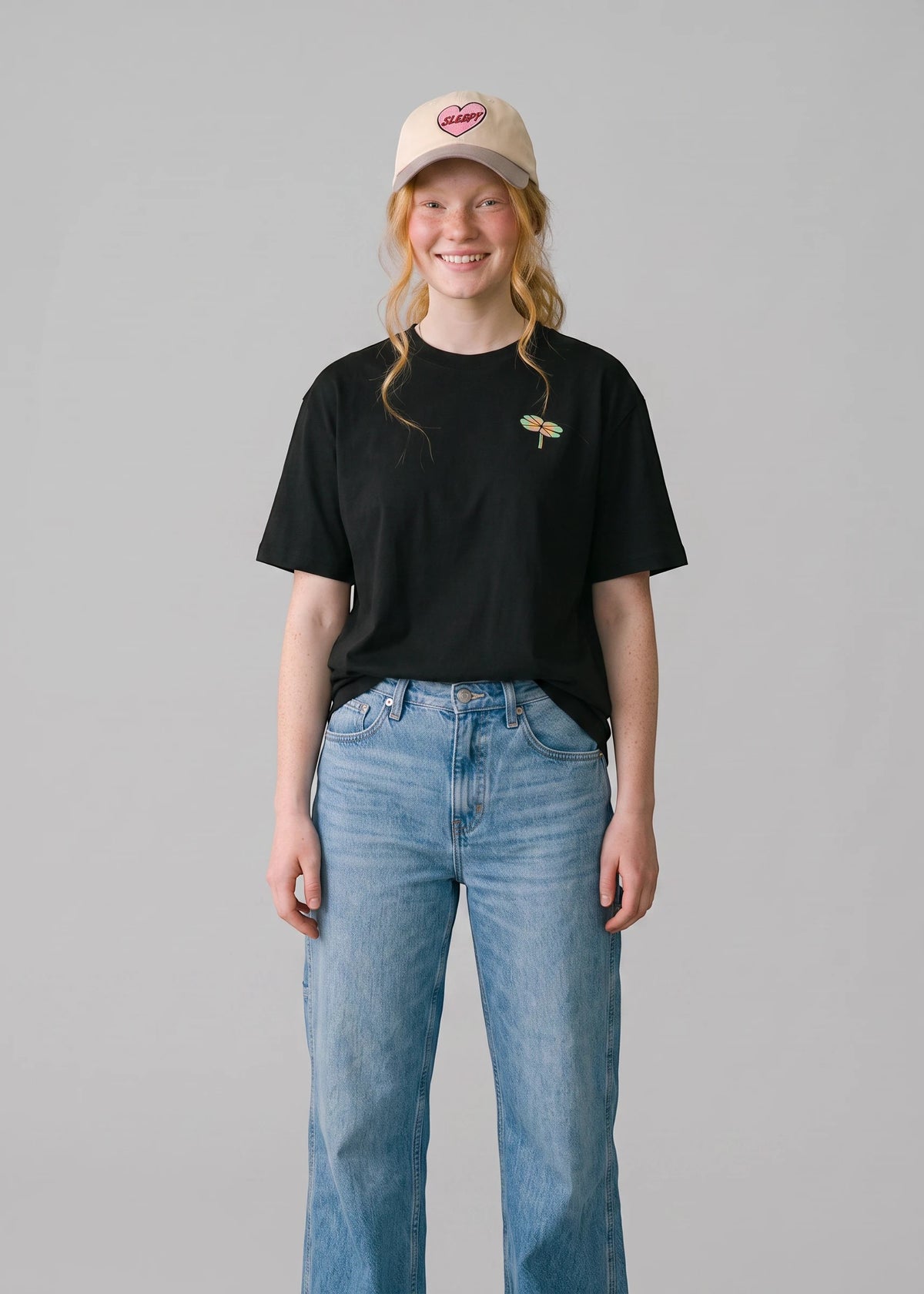 Via Artists Helcovell Guard black oversized cotton t-shirt with small dragonfly graphic worn by a smiling woman