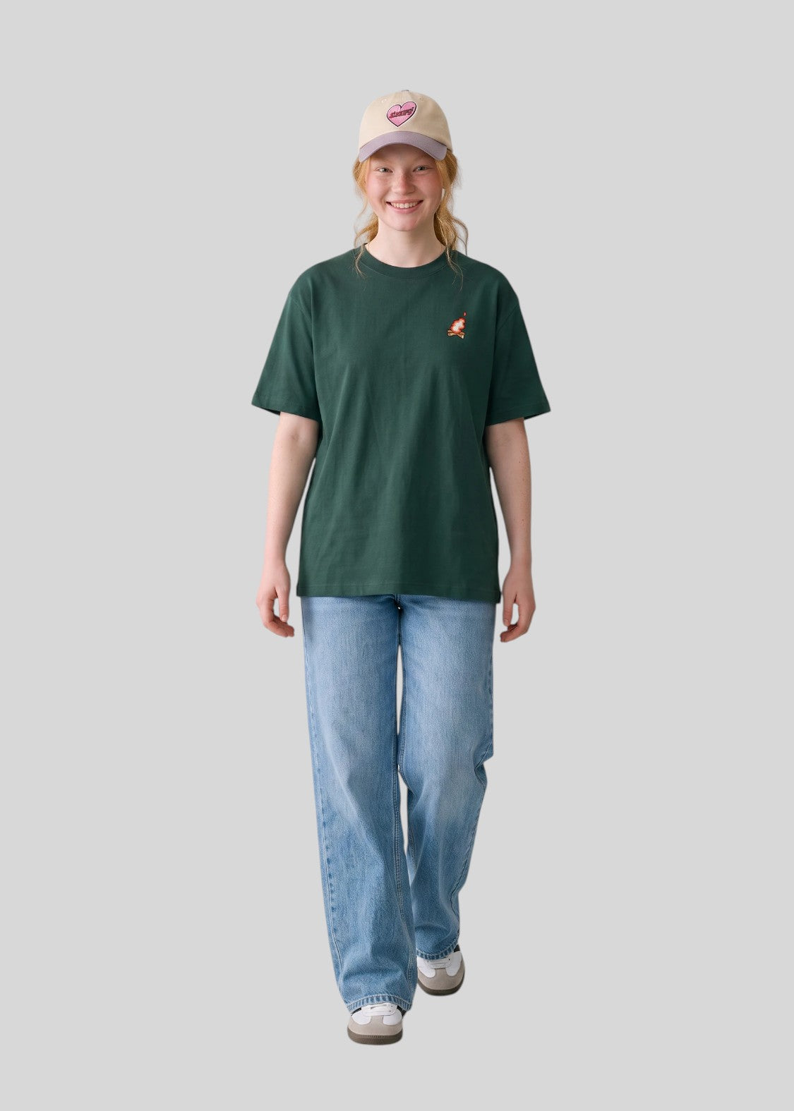 Via Artists Helcovell Rush oversized dark green cotton t-shirt worn by a woman with a beige cap and blue jeans