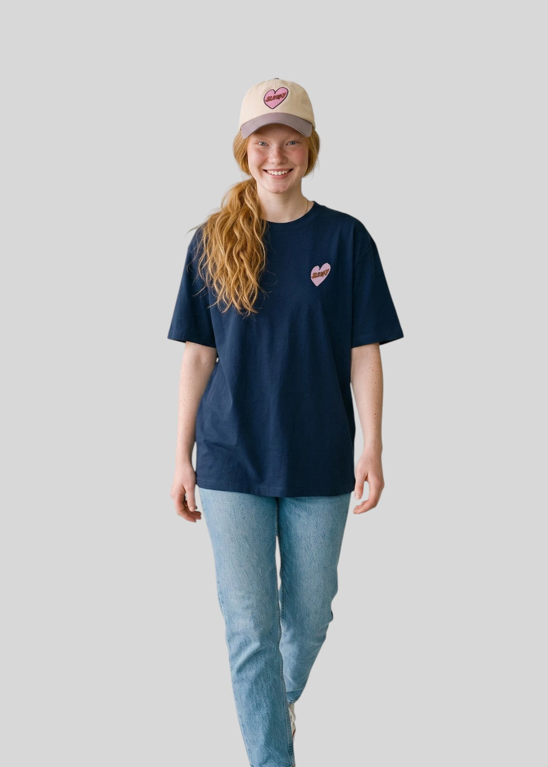 Via Artists Helcovell Sleepy oversized navy cotton t-shirt with pink heart graphic worn by a smiling woman