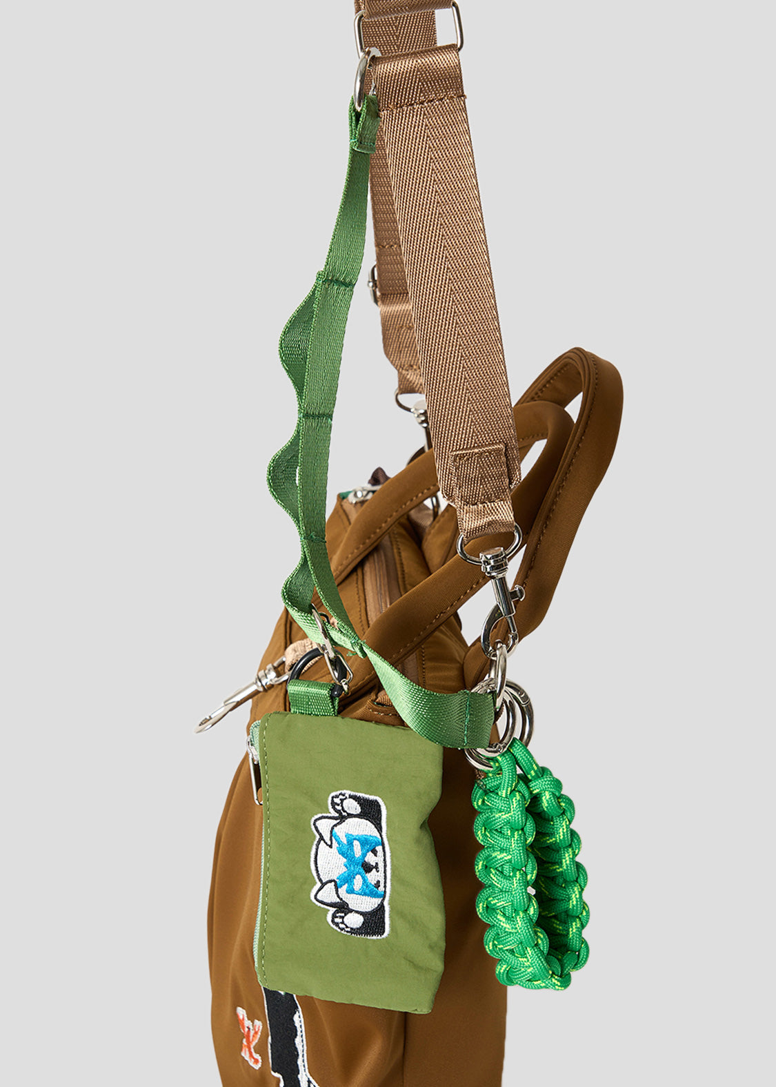 Via Artists Ikaku Lucha mini shoulder bag in brown nylon with green accents, embroidered red panda, and mini pouch.