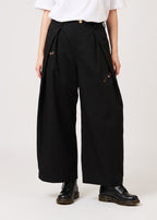 Via Artists Ikaku Royal DRK wide-leg pleated black pants with red panda embroidery, worn with a white top.