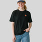 Via Artists Kazukuma Bath oversized black cotton t-shirt with small apple graphic worn by a smiling woman