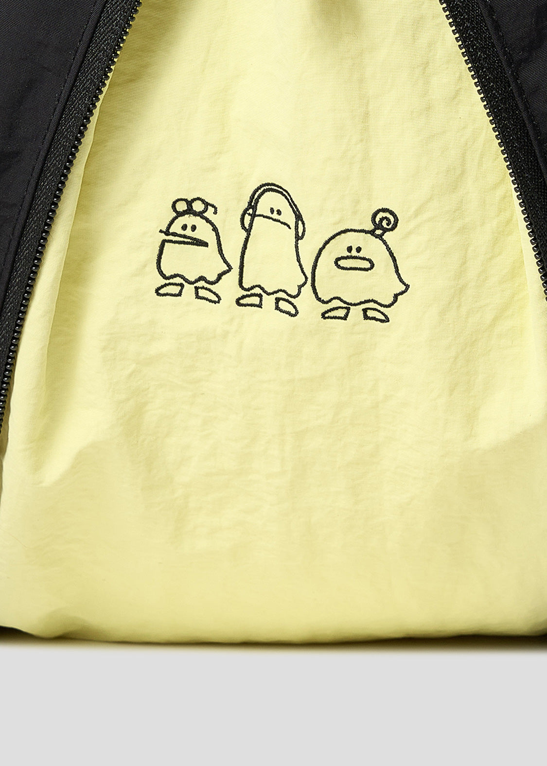 Via Artists Nemuran shoulder bag in pale yellow nylon featuring a black embroidered trio of ghost characters.